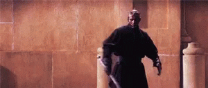 From the movie Star Wars: the Phantom Menace, a humanoid clad in black draws a lightsaber that has two blades.